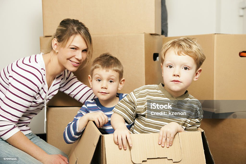 Family moving in their new house Family moving in their new house. The sons are sitting inside the moving boxes, everybody is looking rather cheerful Adult Stock Photo