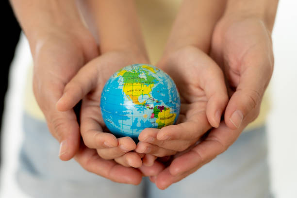 close up photo of mother and child holding hands with a world globe in their hands in better world idea protection and education concept - earth globe mother child imagens e fotografias de stock