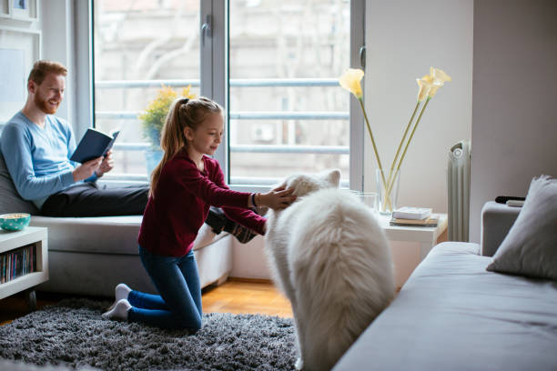 istock Girl playing with dog while dad is reading 980007324
