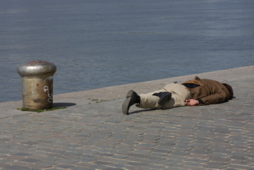 A drunken man is sleeping off his liquor at the quay in sunny Antwerp