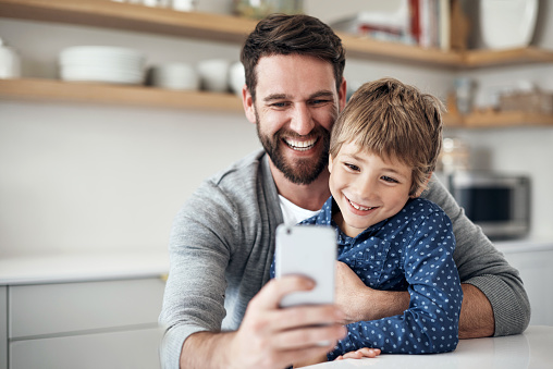 Shot of a father and his little son taking selfies together at home