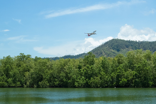 Queensland, Australia – December 11, 2014: A Qantas plane, above the rain forest hills and the Barron River, leaving Cairns in Tropical North Queensland, Australia. Qantas Airways is the third oldest airline in the world.