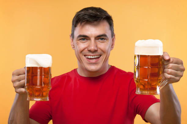 istock Young fit man at Beer Fest, drinking beer on yellow background. 980021890