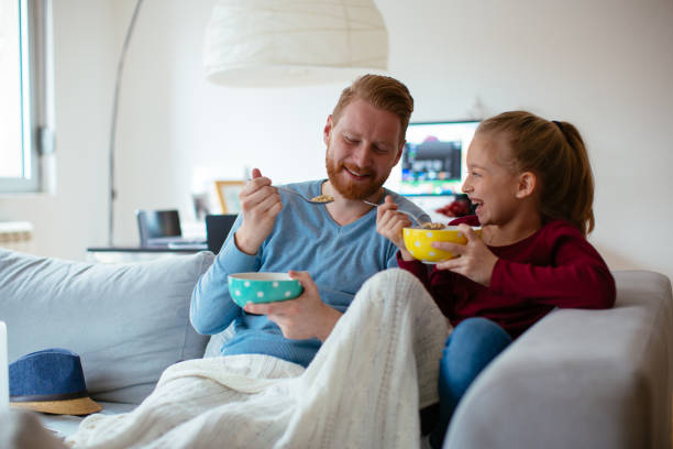 istock Dad and daughter eating cereals on couch 980022822
