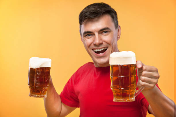istock Young fit man at Beer Fest, drinking beer on yellow background. 980023204