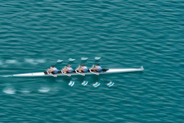 Upper view of quadruple scull rowing team on the water, blurred motion