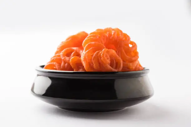 Indian sweet Imarti or Jalebi served in white ceramic plate over white background