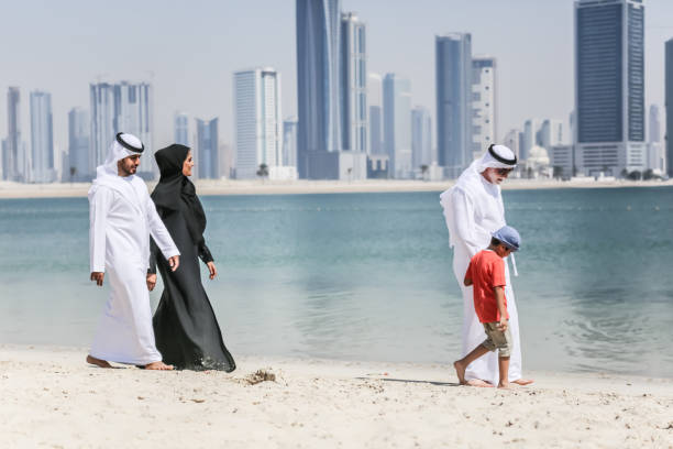 arabische familie, die zu fuß am strand im herbst - bahrain stock-fotos und bilder