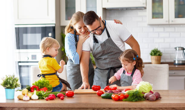 szczęśliwa rodzina z dziećmi przygotowująca sałatkę warzywną - domestic kitchen people fun lifestyles zdjęcia i obrazy z banku zdjęć