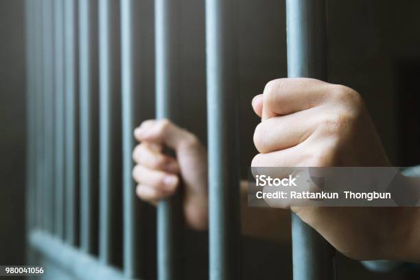 Man In Prison Hands Of Behind Hold Steel Cage Jail Bars Offender Criminal Locked In Jail Stock Photo - Download Image Now