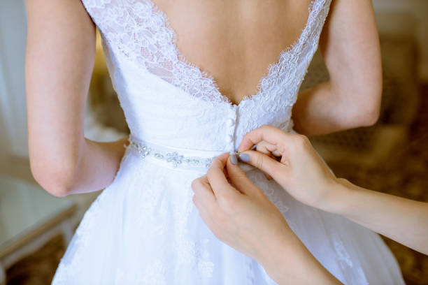 istock Bridesmaid is lacing white wedding dress for beautiful bride 980048224