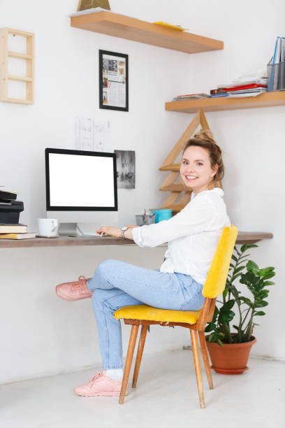 istock Successful pretty young designer girl or remote worker is sitting at workplace with computer. Place for advertising 980049058