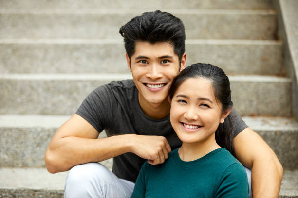 istock Smiling young couple sitting on steps in park 980049838
