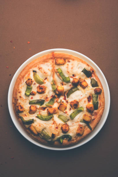 paneer pizza to indyjska wersja włoskiego dania z dodatkiem twarogu, podawana na talerzu z białym sosem. selektywne skupienie - cheeze zdjęcia i obrazy z banku zdjęć