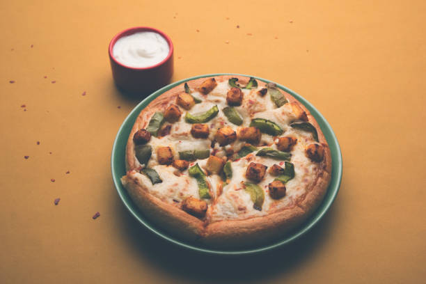 paneer pizza to indyjska wersja włoskiego dania z dodatkiem twarogu, podawana na talerzu z białym sosem. selektywne skupienie - cheeze zdjęcia i obrazy z banku zdjęć