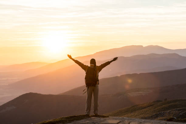 istock Cheerful hiker standing arms outstretched on top mountain 980056626