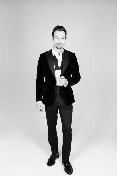istock Young handsome man in a suit, standing and looking at the camera, bow tie undone 980058122