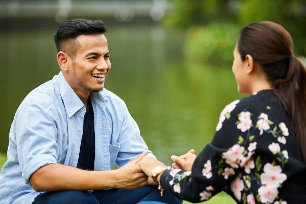 istock Loving couple holding hands while sitting in park 980058408