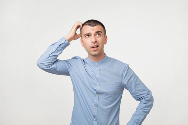 istock Handsome spanish guy in blue shirt, frowning and looking unsatisfied while scratching head 980061152