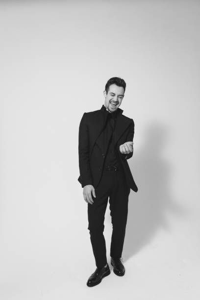 istock Young handsome man in a black suit, laughing and looking at the camera 980061530
