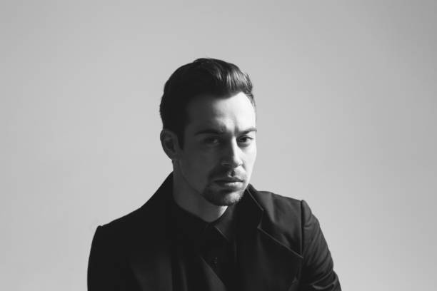 istock Young handsome man in a black suit, seriously looking at the camera 980065102