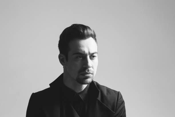 istock Young handsome man in a black suit, seriously looking to the side 980065428