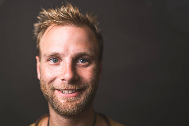 Portrait of mid adult man smiling. Close-up of handsome male is having blond hair. He is against blackboard.