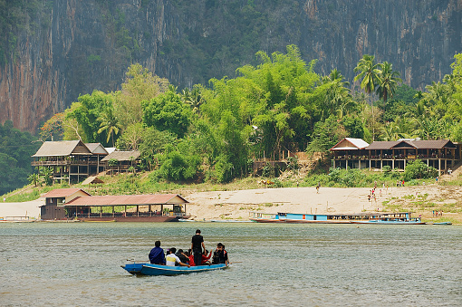 Luang Prabang, Laos - April 12, 2012: Unidentified people cross river by boat at the confluence of the Mekong and the Nam Ou rivers in Luang Prabang, Laos.
