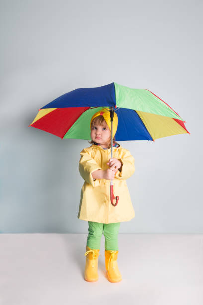 istock Happy funny child with color umbrella posing on wall background. 980066290