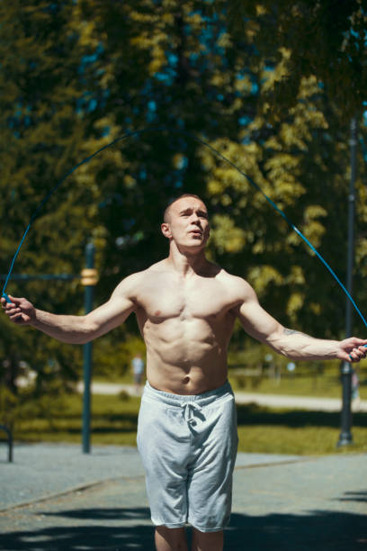 istock Athletic muscular man jumping with a rope, workout outdoors at sunny day 980070760