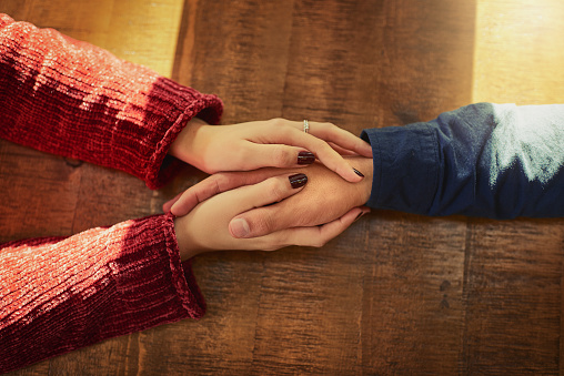 Cropped high angle shot of an unidentifiable man and woman holding hands on a table