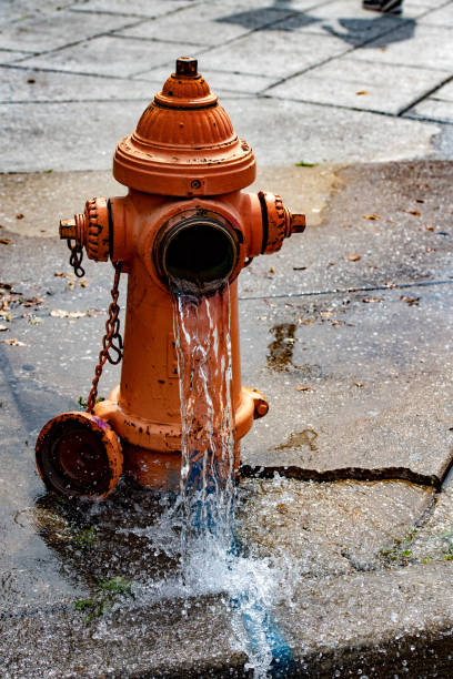 istock Street orange hydrant spreading water on the street 980074594