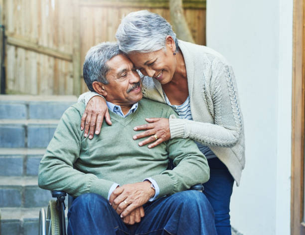 I'm so blessed to have you in my life Shot of a cheerful elderly man seated in a wheelchair while being held by his loving wife outside at home during the day medicare stock pictures, royalty-free photos & images