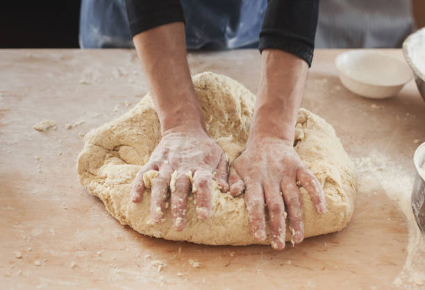 istock Chef hands kneading dough on wooden table 980087778