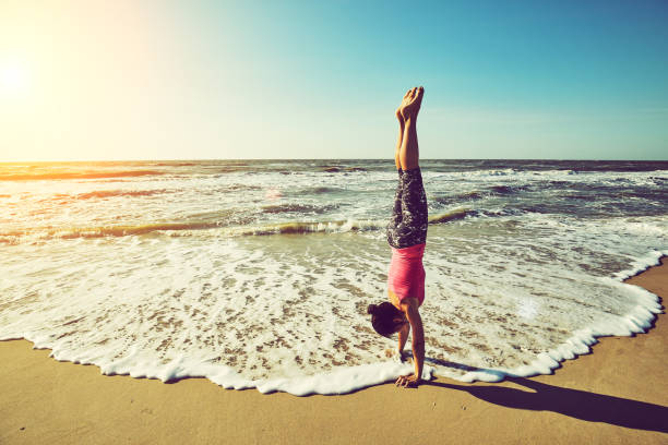 Woman meditating in yoga vrksasana tree pose silhouette at the ocean