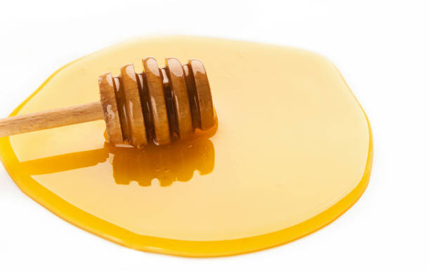 istock Honey and wooden dipper isolated on white 980091346