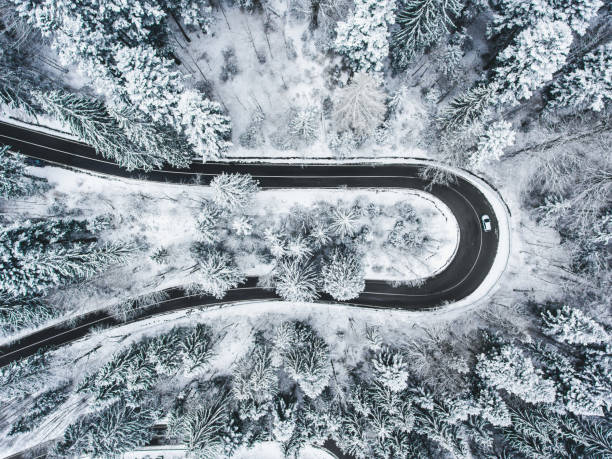 istock White car passing on an extreme winding road in wintertime 980094986