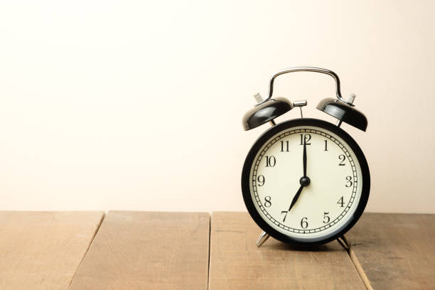 istock black vintage alarm clock close to the window present seven o'clock 980097184