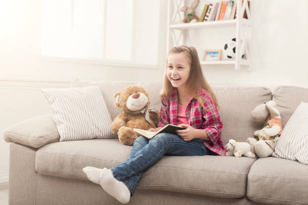 istock Happy little child reading book for her teddy bear 980099482