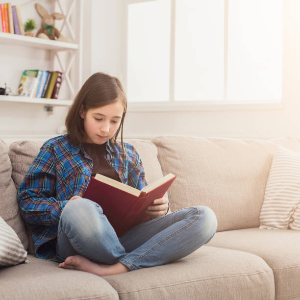 istock Cozy home. Young thoughtful girl with book 980100030