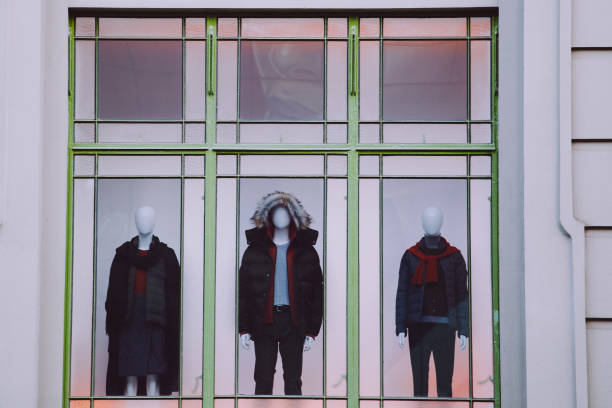 istock Three mannequins with clothes in storefront window closeup 980101314