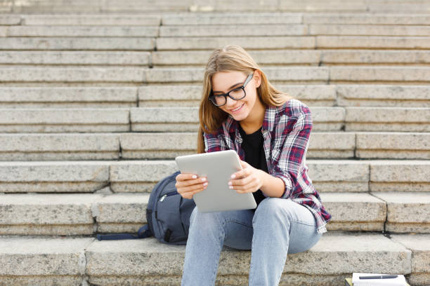istock Happy young woman using digital tablet outdoors 980105870