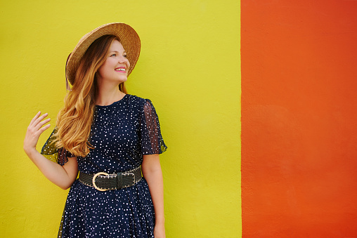 Cropped shot of a beautiful young woman posing against a bright yellow and orange wall outside