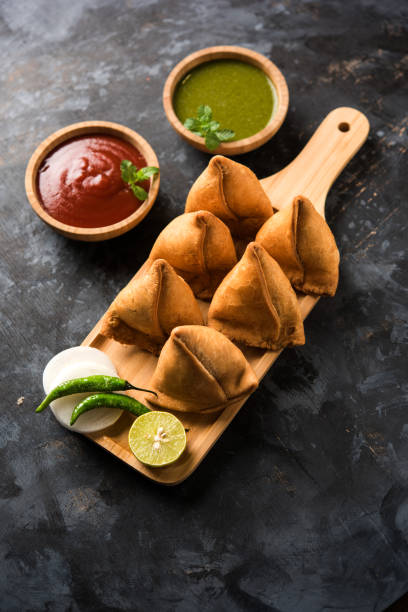 Samosa snack served with tomato ketchup and mint chutney