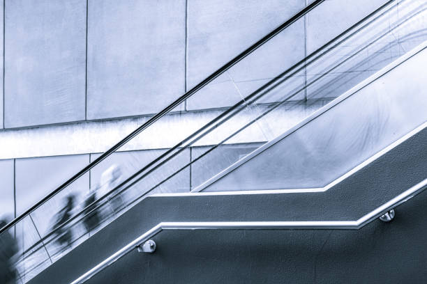 istock Blurred motion of people on escalator with copy space in black and white 980113932