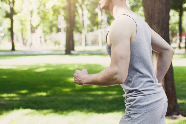 istock Young man running in green park, copy space 980114352