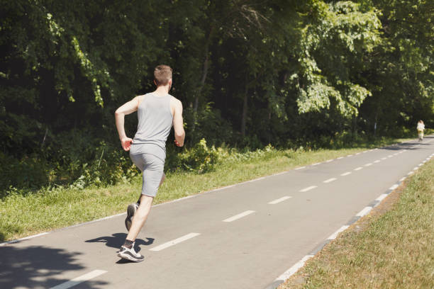 istock Young man jogging on treadmill in park, copy space 980114464
