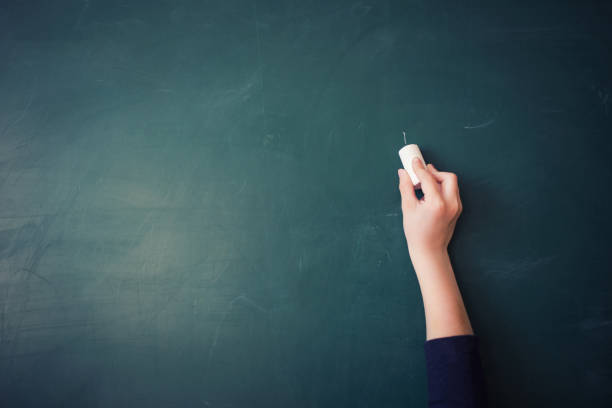 istock children's hand writes chalk on green blackboard in classroom 980117814