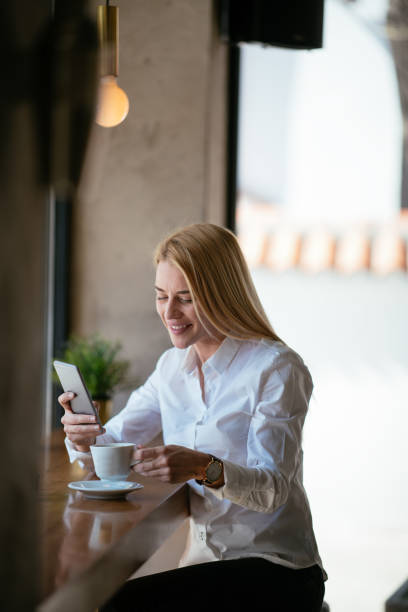 istock Smiling woman using smartphone in cafe bar 980118880