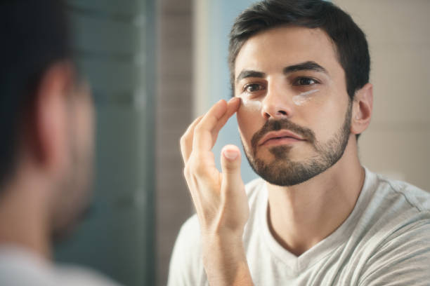 fot de jovem homem aplicando loção de anti-aging skin care - aparência - fotografias e filmes do acervo